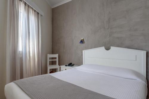 a bedroom with a white bed and a window at Anemomilos in Oia