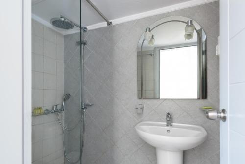 a bathroom with a sink and a shower with a mirror at Anemomilos in Oia