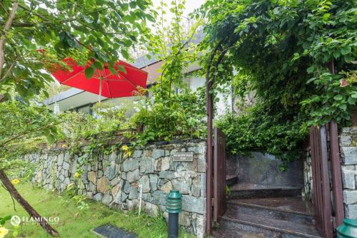 a stone wall with a red umbrella on top of it at FLAMINGOS Villa Happy 3 phòng ngủ- view Hồ- bể bơi riêng in Ngọc Quang
