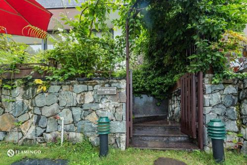 an entrance to a stone wall with a wooden gate at FLAMINGOS Villa Happy 3 phòng ngủ- view Hồ- bể bơi riêng in Ngọc Quang