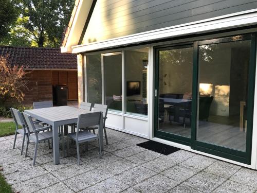 une extension en verre d'une maison avec une table et des chaises dans l'établissement Villa Anna with sauna in Winterswijk, à Winterswijk
