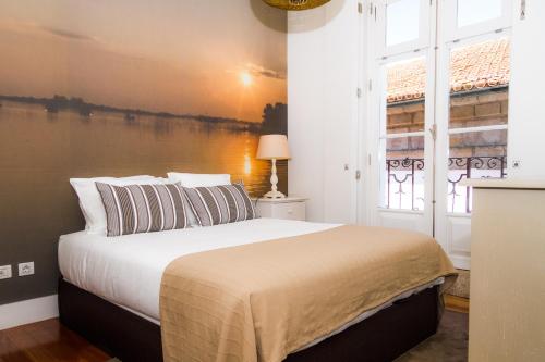 een slaapkamer met een groot bed en een groot raam bij Liiiving in Porto | Ribeira Boutique Apartment in Porto