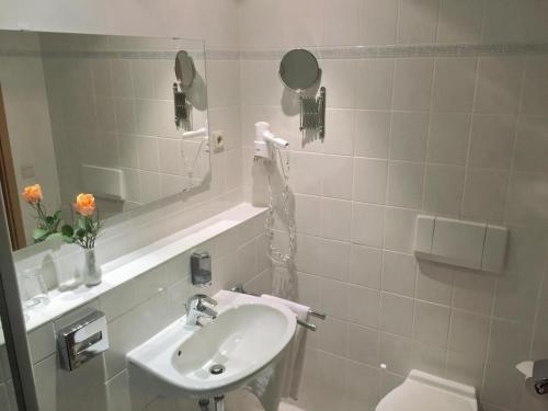 ein Badezimmer mit einem Waschbecken, einem WC und einem Spiegel in der Unterkunft Schneiderlein Hotel in Limbach - Oberfrohna