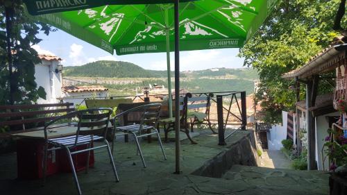 a table and chairs under a green umbrella at Hikers Hostel in Veliko Tŭrnovo
