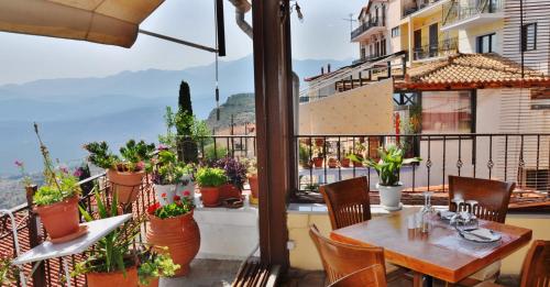 un balcone con tavolo, sedie e piante in vaso. di Iniohos Hotel a Delfi