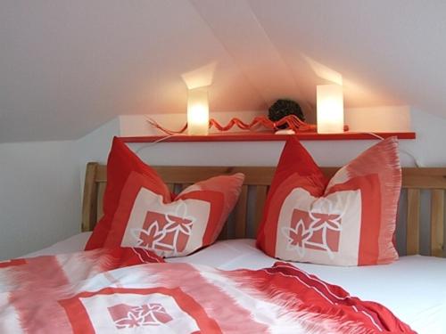 a bed with two red and white pillows and two lights at Ferienwohnung Kranichzug in Kargow