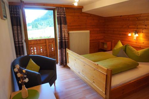 een slaapkamer met een bed, een stoel en een raam bij Ferienhaus Melmer Florian in Sankt Leonhard im Pitztal