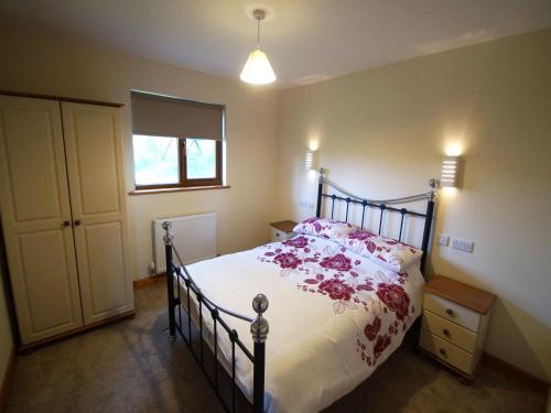 a bedroom with a bed with pink flowers on it at LLanddewi Retreat in Llanddewi Ystradenny