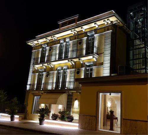 a large yellow building with a balcony at night at Hotel Villa Traiano in Benevento