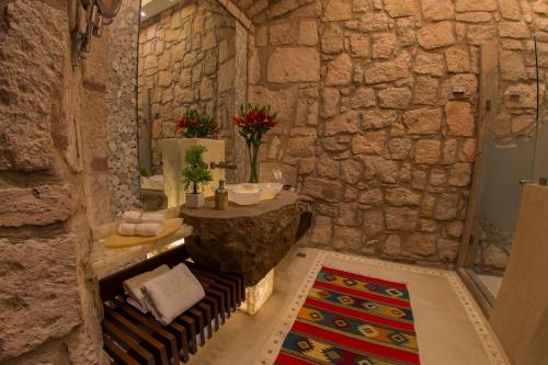 a bathroom with a stone wall with a tub and a sink at Hotel De La Soledad in Morelia