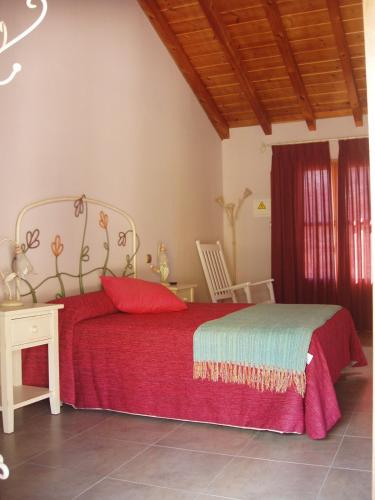 a bedroom with a bed with a red blanket and a table at Las Fontaninas in Noceda del Bierzo
