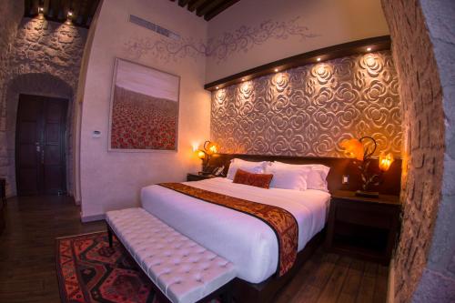 a bedroom with a large bed with a bench in it at Hotel De La Soledad in Morelia