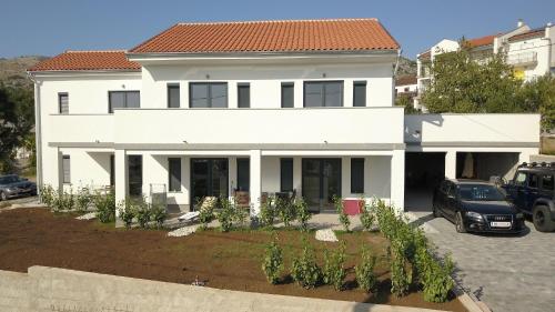 a white house with a car parked in a parking lot at BC Eleven - mit Zentralheizung in Senj