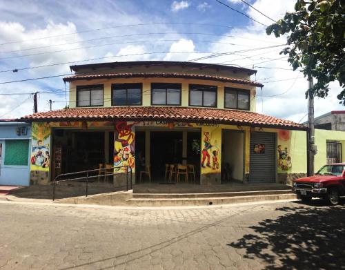a yellow house with a red car parked in front of it at Hotel Casa Vínculos in Estelí