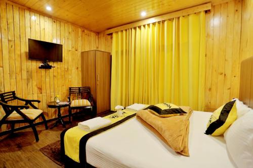 Amara Resorts Manali في مانالي: غرفة نوم بسرير وكرسي وتلفزيون