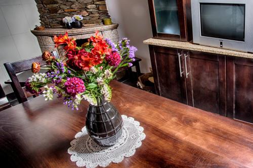 a vase filled with flowers on a wooden table at Casas Peralta - Leira Pereira in Cabreiros