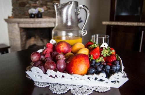 un bol de fruits sur une table avec un pichet de jus dans l'établissement Casas Peralta - Leira Pereira, à Cabreiros