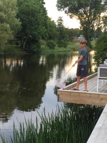 a young boy standing on a dock with a stick in the water at Hotell Villa Rönne in Ängelholm