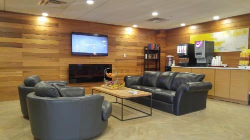 uma sala de espera com duas cadeiras de couro e uma televisão de ecrã plano em Wabasca Inn em Wabasca