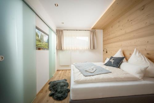 una camera con un letto bianco e una parete in legno di Stoaberg Lodge a Sankt Ulrich am Pillersee