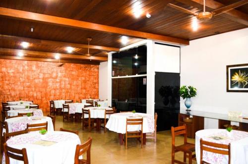 uma sala de jantar com mesas e cadeiras brancas em Taba Hotel em Jaciara