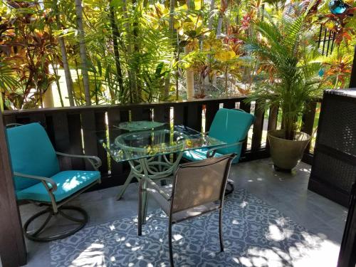 a glass table and chairs on a balcony with plants at Maui Tranquility in Kihei