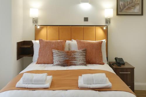 a bedroom with a large bed with two pillows at Imperial Guest House Ltd. in Hounslow