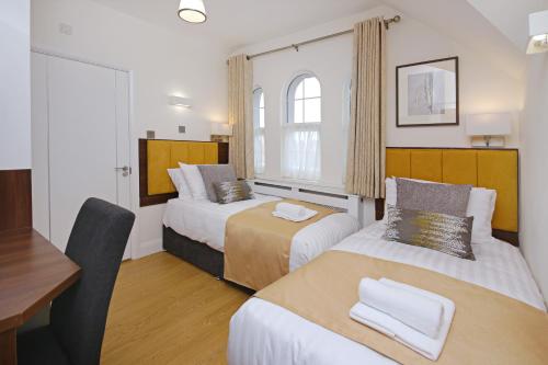 ハウンズローにあるインペリアル ゲストハウス Ltd.のベッド2台とデスクが備わるホテルルームです。