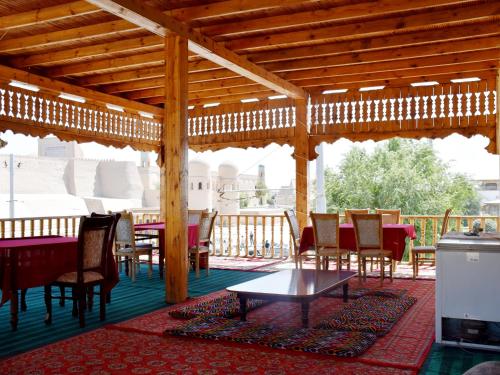Khiva Alibek B&B & Travel في خيوة: جناح خشبي مع طاولات وكراسي على فناء