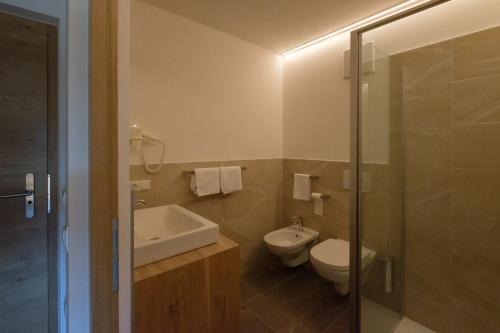 a bathroom with a toilet and a sink and a shower at Gasthof Löwen in Nova Levante