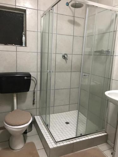 a bathroom with a shower with a toilet and a sink at Ian and Pam's Flatlet in Empangeni