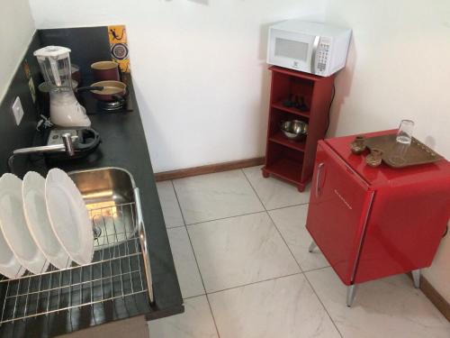 Elle comprend une petite cuisine équipée d'un réfrigérateur rouge et d'un four micro-ondes. dans l'établissement Suites Vida Mansa, à Maresias