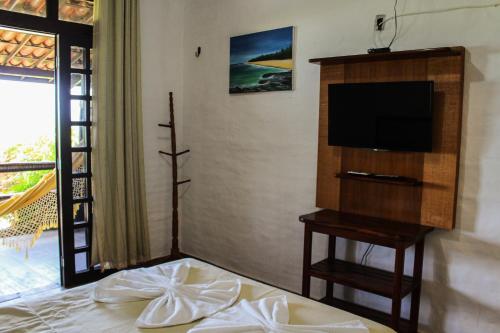 um quarto com uma cama, uma televisão e uma mesa em Pousada Vira Sol em Trairi