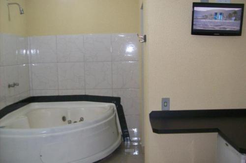 a bathroom with a tub and a tv on the wall at Hotel Pousada Village in Sorocaba