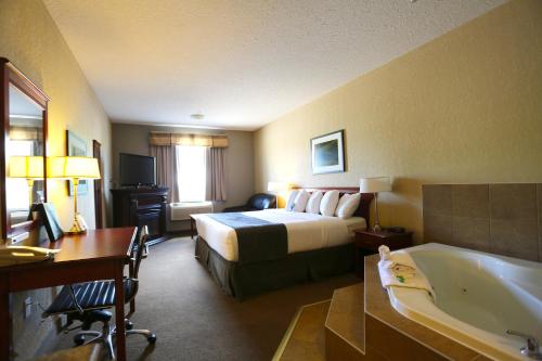 - une chambre d'hôtel avec un lit et une baignoire dans l'établissement Lakeview Inns & Suites - Fort Nelson, à Fort Nelson