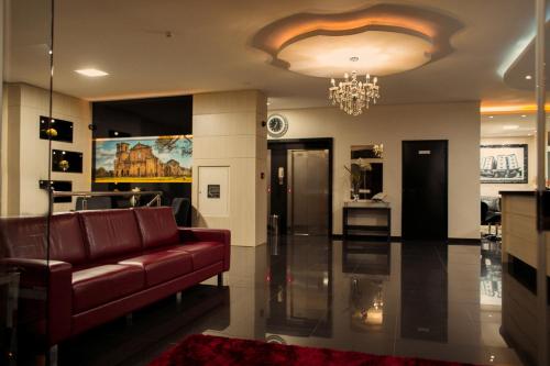 uma sala de estar com um sofá vermelho e um lustre em Benos Hotel em Santa Rosa