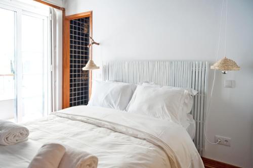 a white bed with white pillows and a window at Lemon Tree Stay in Faro