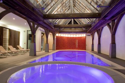 a large swimming pool in a building with a wooden ceiling at Logis Hotel Le Parc & Spa in Saint-Hippolyte
