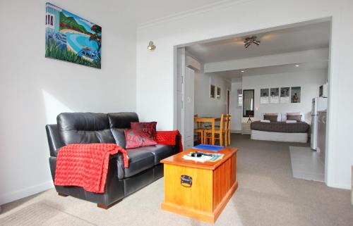 a living room with a black leather couch and a table at Blue Marlin Apartments in Whitianga