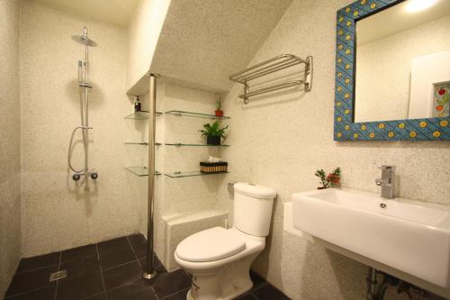 ein Badezimmer mit einem WC, einem Waschbecken und einem Spiegel in der Unterkunft OS Homestay in Nanwan