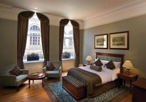 a bedroom with a bed and a chair and two windows at Quebecs in Leeds