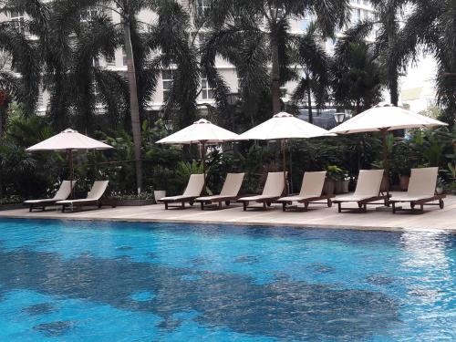 a group of chairs and umbrellas next to a swimming pool at Bluesky Serviced Apartment Airport Plaza in Ho Chi Minh City
