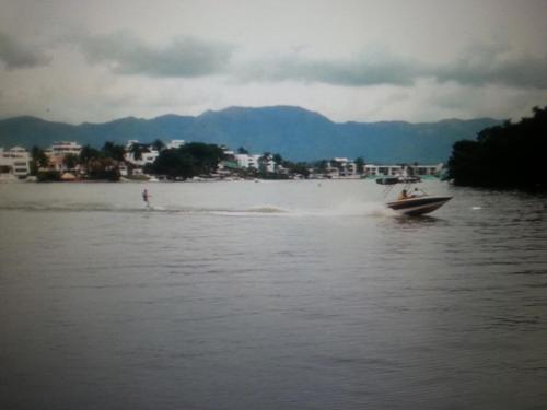 a boat on a body of water with a person water skiing at HERMOSA CASAQUINTA FAMILIAR CONDOMINIO CAMPESTRE EL PEÑON Piscina Privada Campo de Golf in Girardot