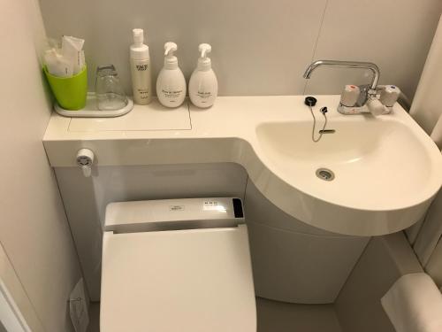 a white bathroom with a sink and a toilet at Hotel Crown Hills Iwaki in Iwaki