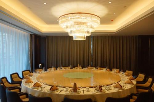 a large table in a room with chairs and a chandelier at Yantai Meiya International ApartHotel (Previous Ramada Plaza) in Yantai