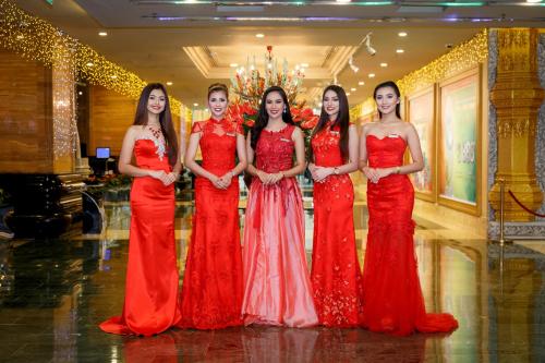 three women dressed in red and white posing for a picture at NagaWorld Hotel & Entertainment Complex in Phnom Penh