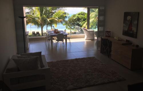 a living room with a table and a view of the ocean at Pearly Sands - Beachfront Deluxe Apartment in Roches Noires