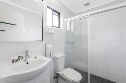 a white bathroom with a toilet and a sink at Mercure Wagga Wagga in Wagga Wagga