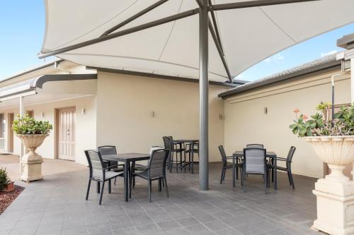 a patio with tables and chairs under an umbrella at Mercure Wagga Wagga in Wagga Wagga