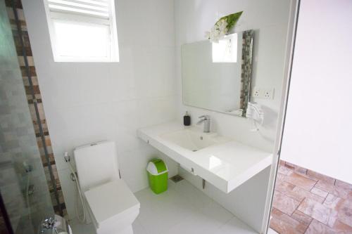 a white bathroom with a sink and a toilet at Villa The Leaf in Weligama